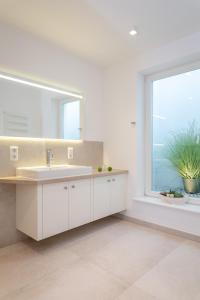 a white bathroom with a sink and a window at Bäum Hüs A in Westerland (Sylt)