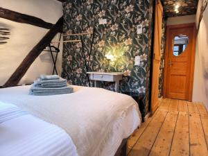 a bedroom with a bed and a wall with floral wallpaper at petite maison am Mühlenberg in Monschau