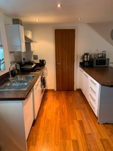 a kitchen with white cabinets and a wooden floor at 2 Bed duplex, close to Millennium Square in Leeds