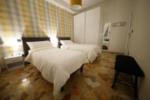 una camera con due letti con lenzuola bianche e una sedia di Venezia House a Mestre