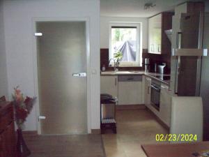 eine Küche mit einer Tür, die sich zu einer Küche mit einer Spüle öffnet in der Unterkunft Villa Rogge in Berlin
