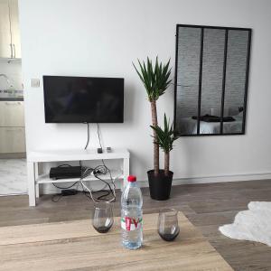 a living room with a bottle of water and two glasses at Studio Cosy Elancourt, Les terrasses d'Héricé in Élancourt