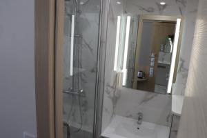 a bathroom with a shower and a sink and a mirror at Geographotel Paris-Roissy CDG Airport in Le Mesnil-Amelot