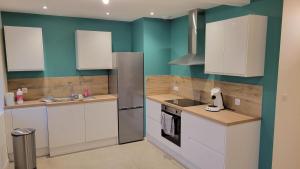 a kitchen with white cabinets and green walls at Appartement neuf avec terrasse in Montmerle Sur Saône