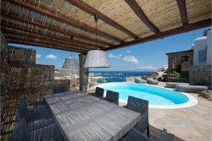 un patio con una mesa y una piscina en Luxury Mykonos Villa - 3 Bedrooms - Villa Vigor - Stunning Sea Views - Agios Lazaros, en Psarou