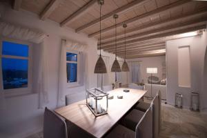 uma sala de jantar com uma mesa de madeira e cadeiras em Luxury Mykonos Villa - 3 Bedrooms - Villa Vigor - Stunning Sea Views - Agios Lazaros em Psarou