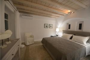 um quarto branco com uma cama e uma cadeira em Luxury Mykonos Villa - 3 Bedrooms - Villa Vigor - Stunning Sea Views - Agios Lazaros em Psarou