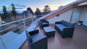 a balcony with couches and tables on a roof at Appartement neuf avec terrasse in Montmerle Sur Saône