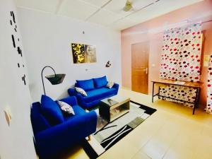 una sala de estar con 2 sofás azules y una pared en Eden Meublé en Uagadugú
