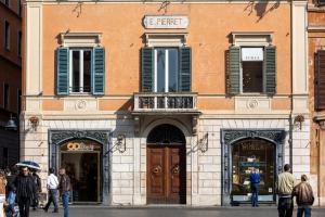 un bâtiment avec des volets bleus et des personnes marchant dans une rue dans l'établissement Residenza Pierret, à Rome