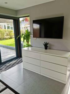 a living room with a tv and a white dresser at Natures Corner in Aldenham