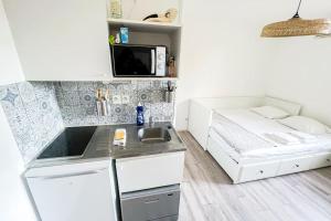 een kleine keuken met een wastafel en een bed bij At the foot of the ramparts in a secure residence in Avignon