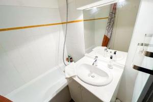 een witte badkamer met een wastafel en een bad bij At the foot of the ramparts in a secure residence in Avignon