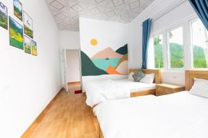 two beds in a room with a mural on the wall at Cat Ba Countryside Homestay in Cat Ba
