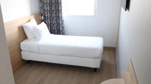 a white couch in a room with a window at Geographotel Paris-Roissy CDG Airport in Le Mesnil-Amelot