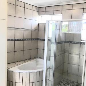 a bathroom with a shower with a bath tub at Royal Taste of Africa Apartments in Windhoek
