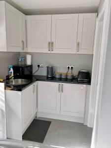 a kitchen with white cabinets and a sink at Natures Corner in Aldenham