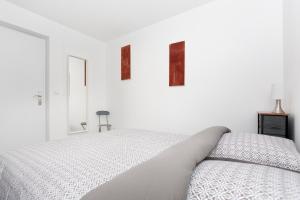 een witte slaapkamer met een bed en twee foto's aan de muur bij Côté Jardin 2 - Appartement avec Jardin in Le Coteau