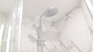 a shower with a shower head in a bathroom at Geographotel Paris-Roissy CDG Airport in Le Mesnil-Amelot