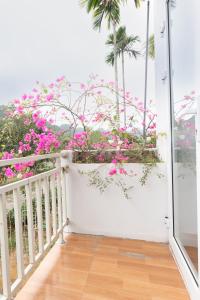 a balcony with pink flowers and palm trees at Cat Ba Countryside Homestay in Cat Ba
