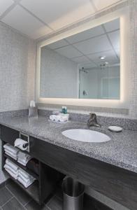 La salle de bains est pourvue d'un lavabo et d'un grand miroir. dans l'établissement Holiday Inn Express Nags Head Oceanfront, an IHG Hotel, à Nags Head