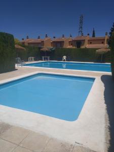 a swimming pool with blue water in front of a house at Casa familiar con dos piscinas entre la playa y la ciudad in Otura