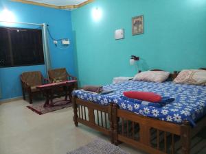 een slaapkamer met een bed met een blauwe muur bij Casa Baptista Guest House in Goa