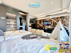 um quarto com uma grande cama branca e uma televisão em Bali Residence Melaka By Heystay Management em Malaca