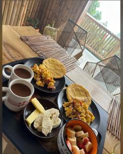 una mesa con dos platos de comida y dos tazas de café en Zioru cabaña, en Belalcázar
