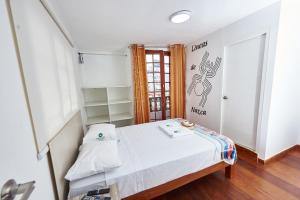Habitación pequeña con cama y puerta en Hostel Prada en Lima