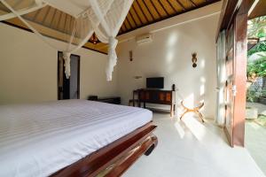 une chambre avec un lit et une télévision dans l'établissement Cantik ArtVilla for big company by ArthouseBali, à Uluwatu