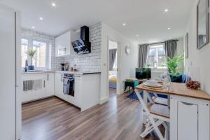 倫敦的住宿－Modern 1 Bed Apartment - Nine Elms, Battersea，厨房配有白色橱柜和木桌