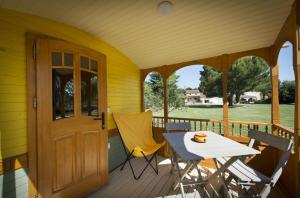eine Veranda mit einem Tisch, Stühlen und einer Tür in der Unterkunft Mas de la Mare in Saint-Andiol