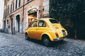 une petite voiture jaune garée sur une rue pavée dans l'établissement Nice and cozy appartment Innside photos are coming soon, à Dogliani