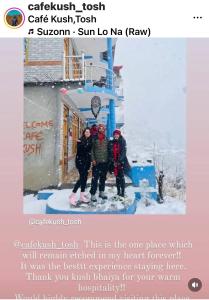 tres personas de pie en la nieve frente a un edificio en Cafekush tosh en Tosh
