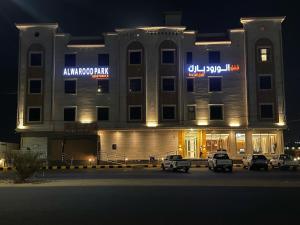 a large building with cars parked in a parking lot at شقق الورود بارك in Al Mikhlaf