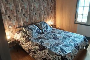 ein Bett mit einer blauen und weißen Bettdecke in einem Schlafzimmer in der Unterkunft Le Gite de Lonzanges in Lanobre