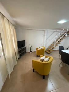 una sala de estar con 2 sillas amarillas y una escalera en Aura en General Fernández Oro
