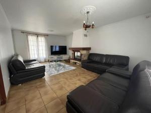 a living room with black leather furniture and a flat screen tv at Maison RNA spacieuse 5 chambres in Saint-Witz