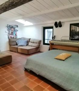 ein Schlafzimmer mit einem Bett, einem Sofa und einem Klavier in der Unterkunft Grande maison en pierre dans la colline varoise in Vidauban