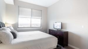 a bedroom with a white bed and a television at Luxury Apartment In Harbor Point in Stamford