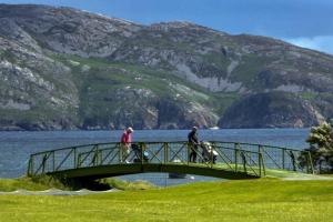two people riding bikes on a bridge over a lake at Portsalon Cottage in Portsalon