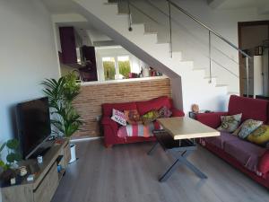 a living room with a red couch and a tv at Casa familiar con dos piscinas entre la playa y la ciudad in Otura