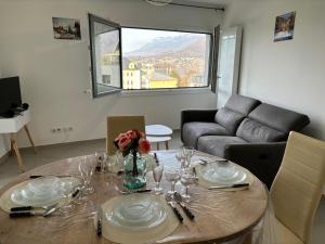 een woonkamer met een tafel met borden en wijnglazen bij View Point Imperial lake in Annecy