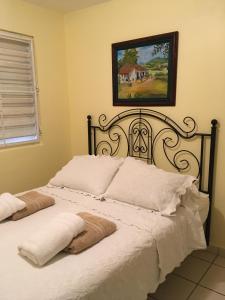 1 cama con sábanas blancas y una foto en la pared en Posada Colonial Beach Villas, en San Juan