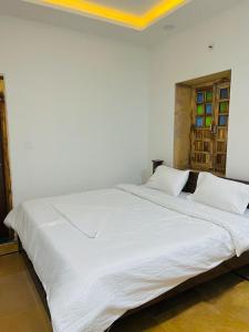 uma grande cama branca com duas almofadas num quarto em Hotel Golden Garh em Jaisalmer