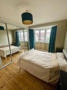 ein Schlafzimmer mit einem großen Bett und einem Spiegel in der Unterkunft Greater London House with excellent transport in Forest Hill