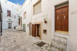 an alley with white buildings and a wooden door at Casa Relax in Mesagne