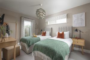 um quarto com 2 camas com lençóis verdes e brancos em Salt Life, Dunes at Upton Towans em Hayle