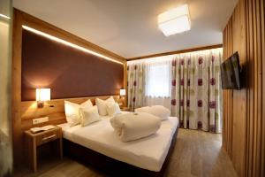 a bedroom with a bed with white sheets and pillows at Hotel Arnika in Ischgl